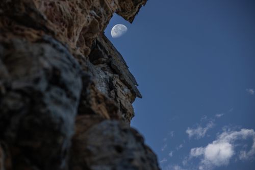 Free Captivating view of the moon above rugged rock against a blue sky, highlighting nature's beauty. Stock Photo