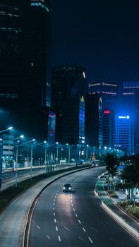 Night view of empty Jakarta city highway with illuminated skyscrapers and street lights.
