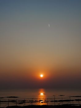 A tranquil sunset over the ocean with warm colors reflecting on the water's surface.