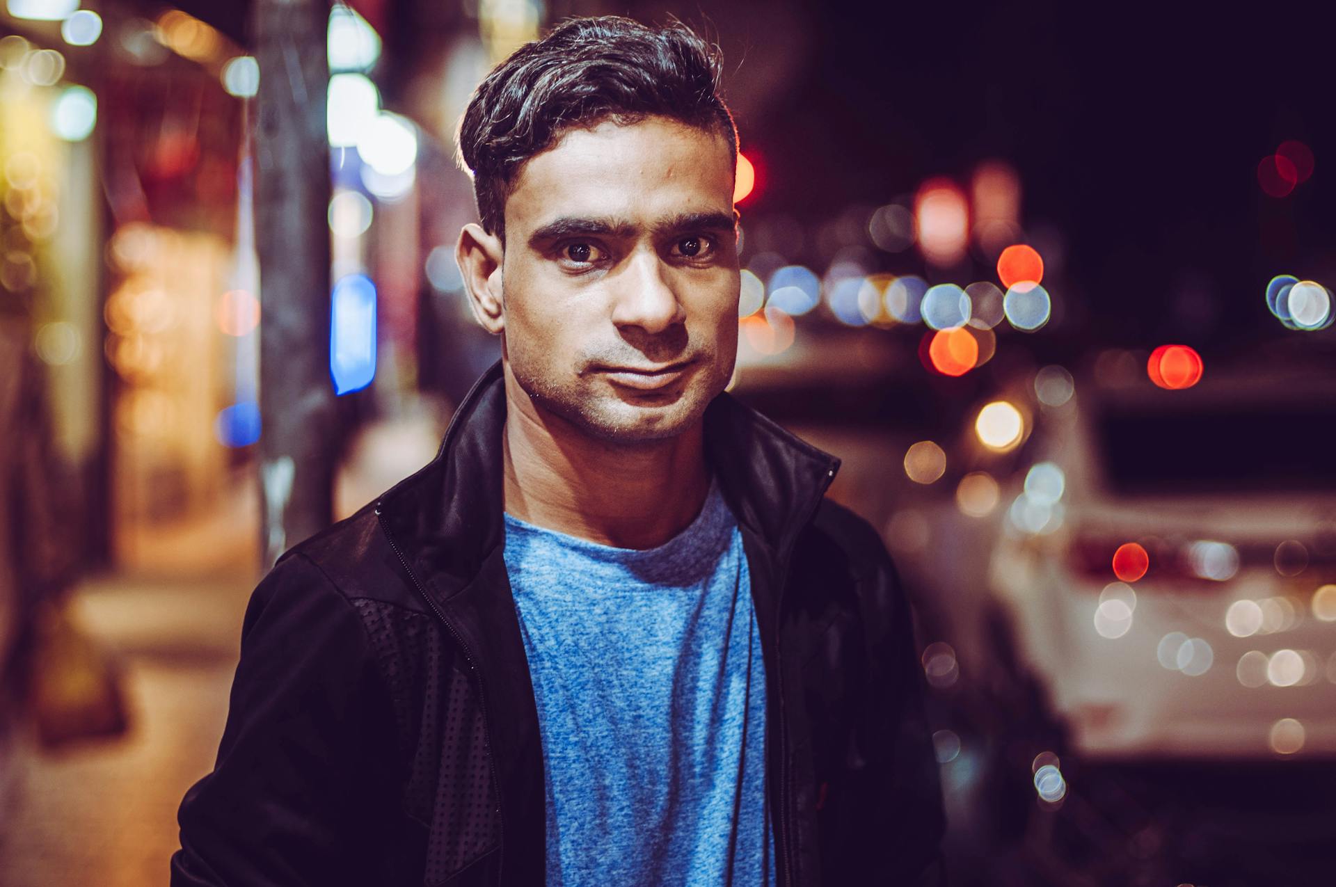 Portrait of a South Asian man at night with city lights bokeh in Karachi, Pakistan.