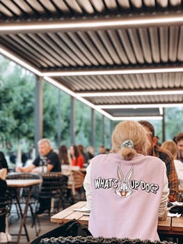A vibrant outdoor dining area with people enjoying their meals, featuring a cartoon-themed sweater.