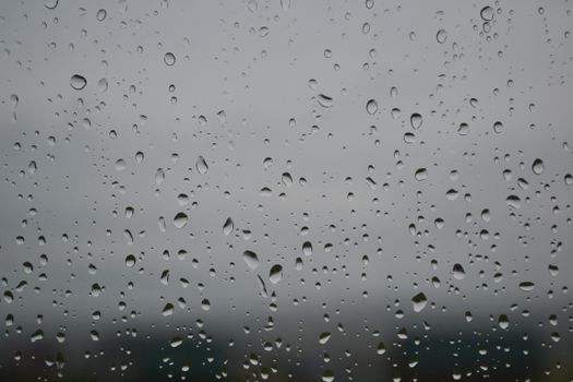 Rainy day view showing water droplets on a window glass, creating a serene atmosphere.