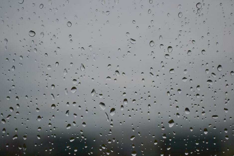 Rainy day view showing water droplets on a window glass, creating a serene atmosphere.
