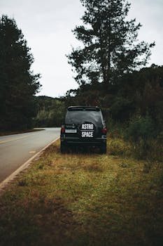 A vehicle with 'Astro Space' parked beside a scenic rural road surrounded by trees.