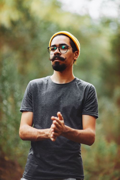 Free A stylish man with glasses and a moustache poses outdoors in a natural setting. Stock Photo