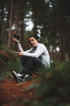 Smiling young man in forest with camera, enjoying nature and photography.