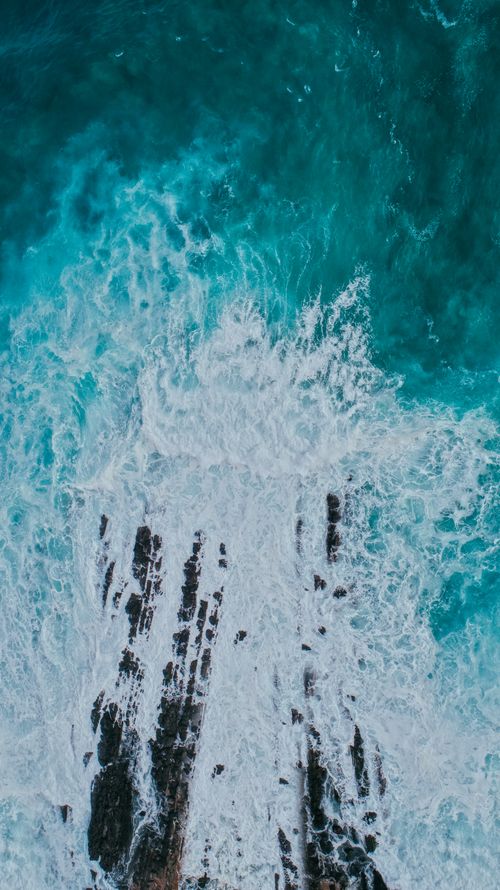 Free Drone shot capturing the dynamic waves crashing over rocks on the coast of Oman. Stock Photo