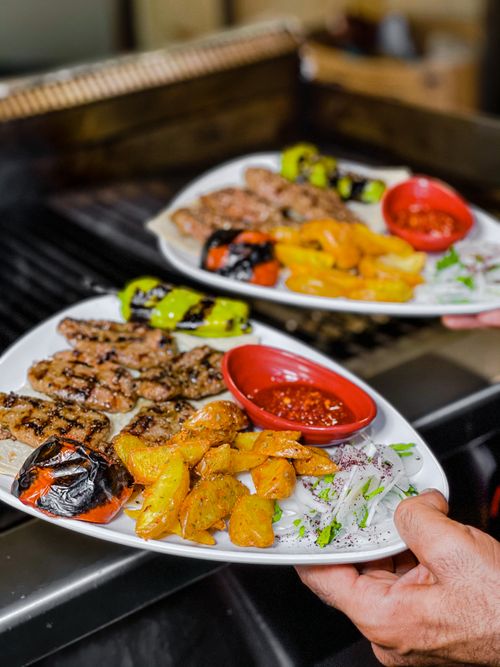 Free Two plates of appetizing grilled kebabs with vegetables and sauces, perfect for a savory meal. Stock Photo