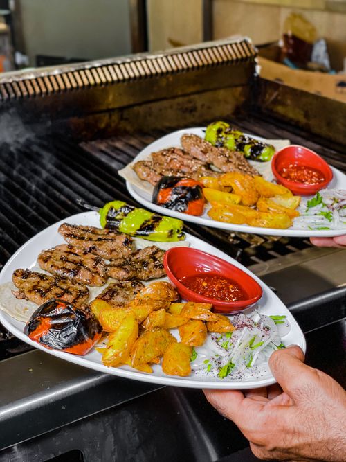 Free Close-up of grilled meat and vegetables served on ceramic plates with spicy sauce. Stock Photo