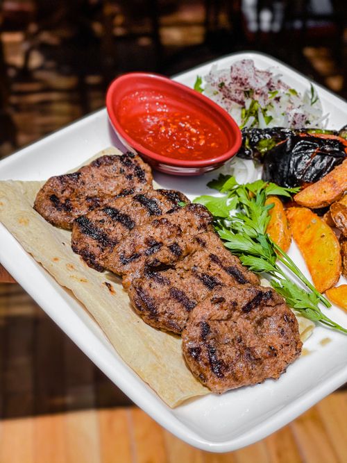 Free Delicious grilled kebabs and vegetables served with sauce on a ceramic plate. Stock Photo