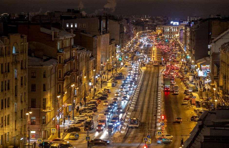A bustling downtown Saint Petersburg at night, showcasing vibrant city lights and busy streets with cars and people.