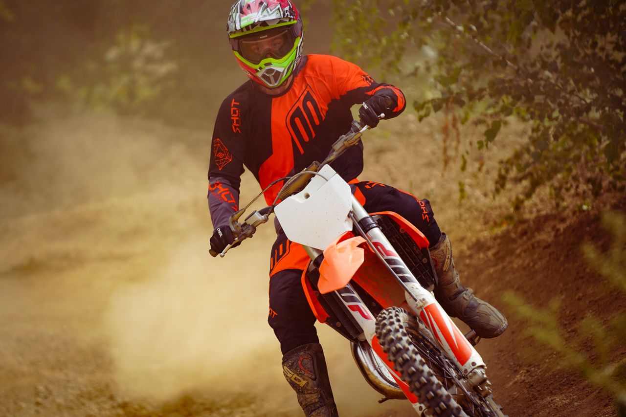 A dirt bike rider kicking up dust on a trail