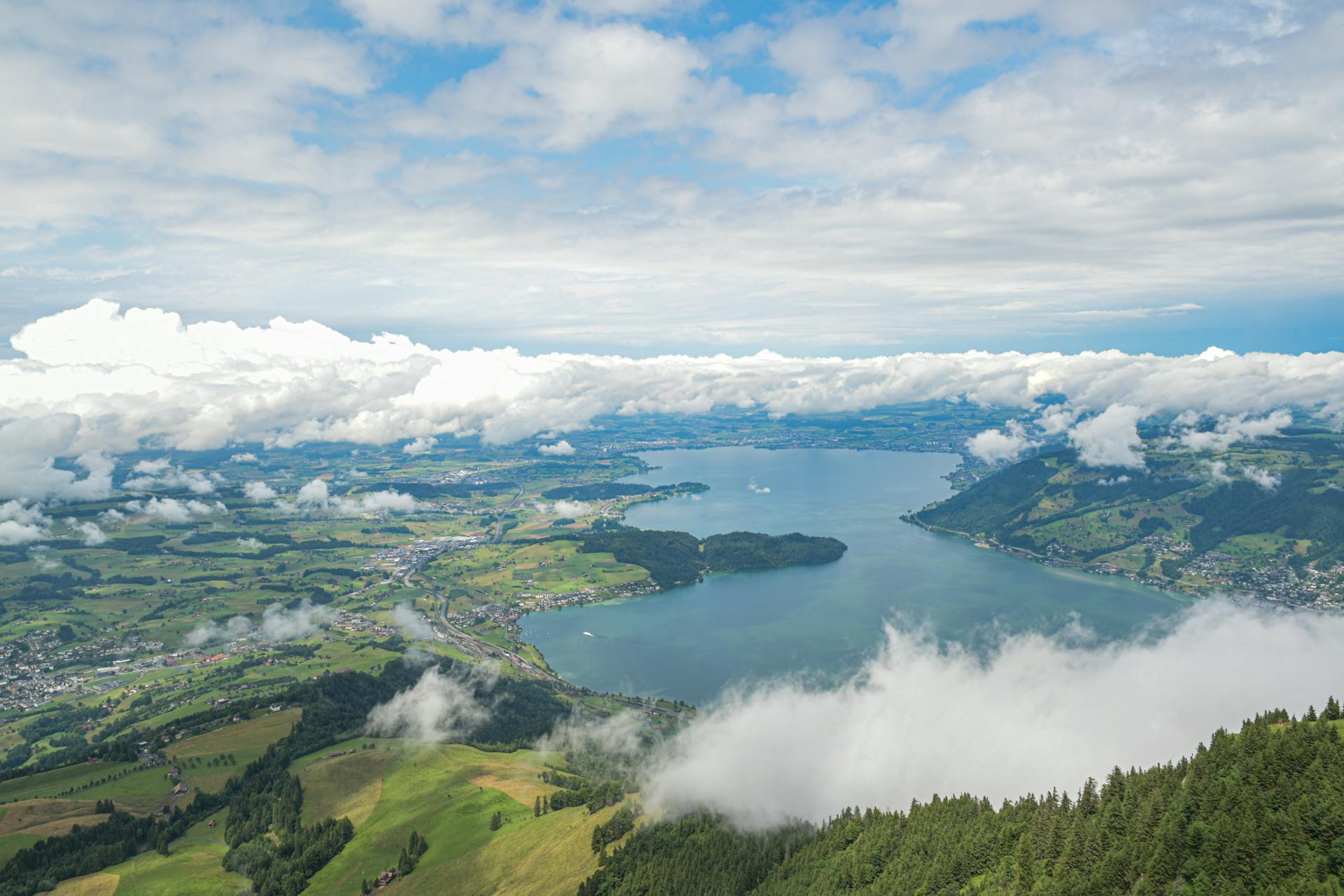 Stunning aerial view of Lake Lucerne surrounded by lush hills and clouds from Rigi Kulm in Switzerland.
