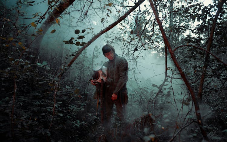 Man In Jacket Holding Helmet In The Forest 