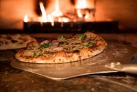 Pizza au four à bois sur pelle en bois