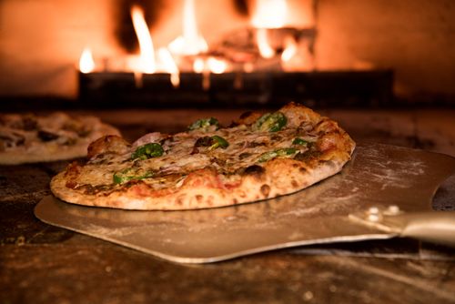 Pizza sortant du four à bois