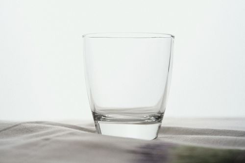 Free Elegant clear glass cup on a soft white surface offers versatile use for minimalistic settings. Stock Photo