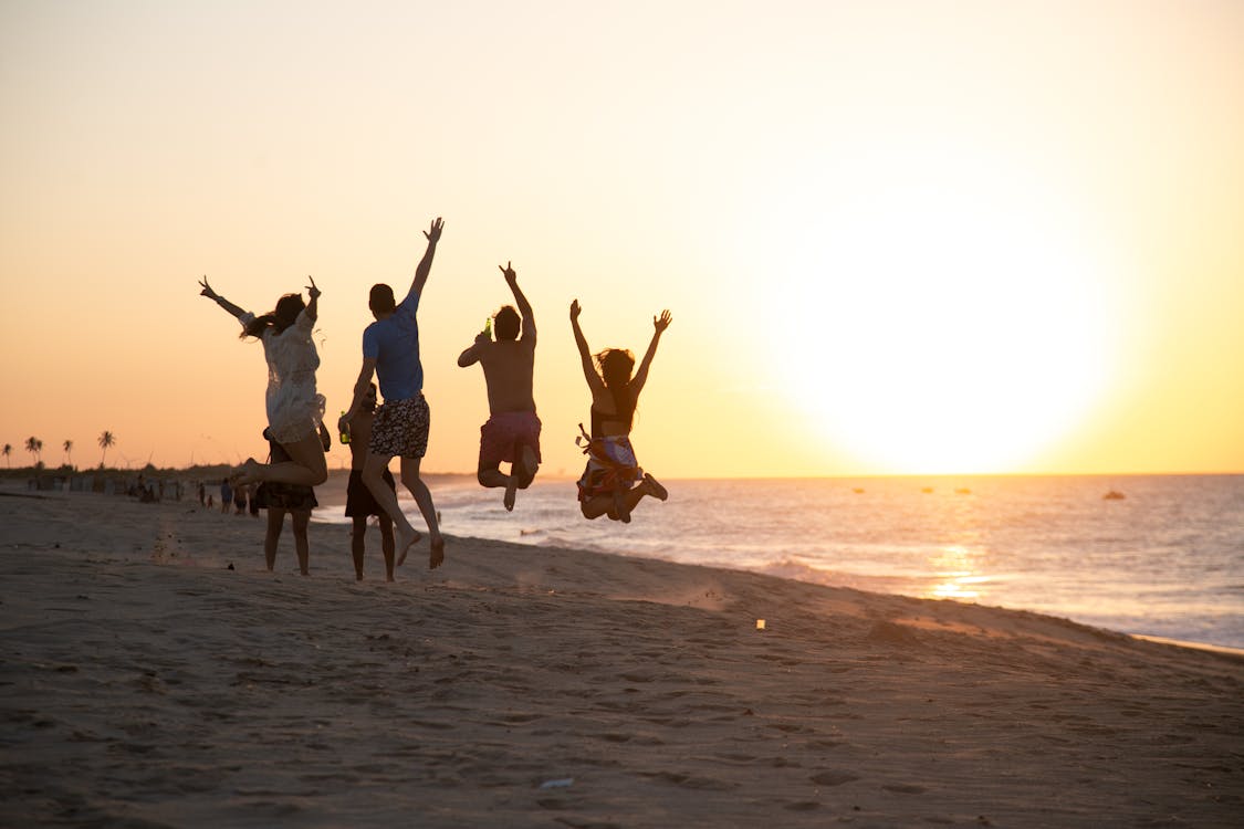 People Jumping on The Beach During Sunset