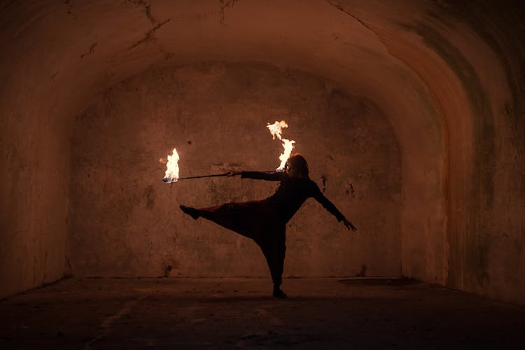 A Man Dancing While Holding A Stick With Fire