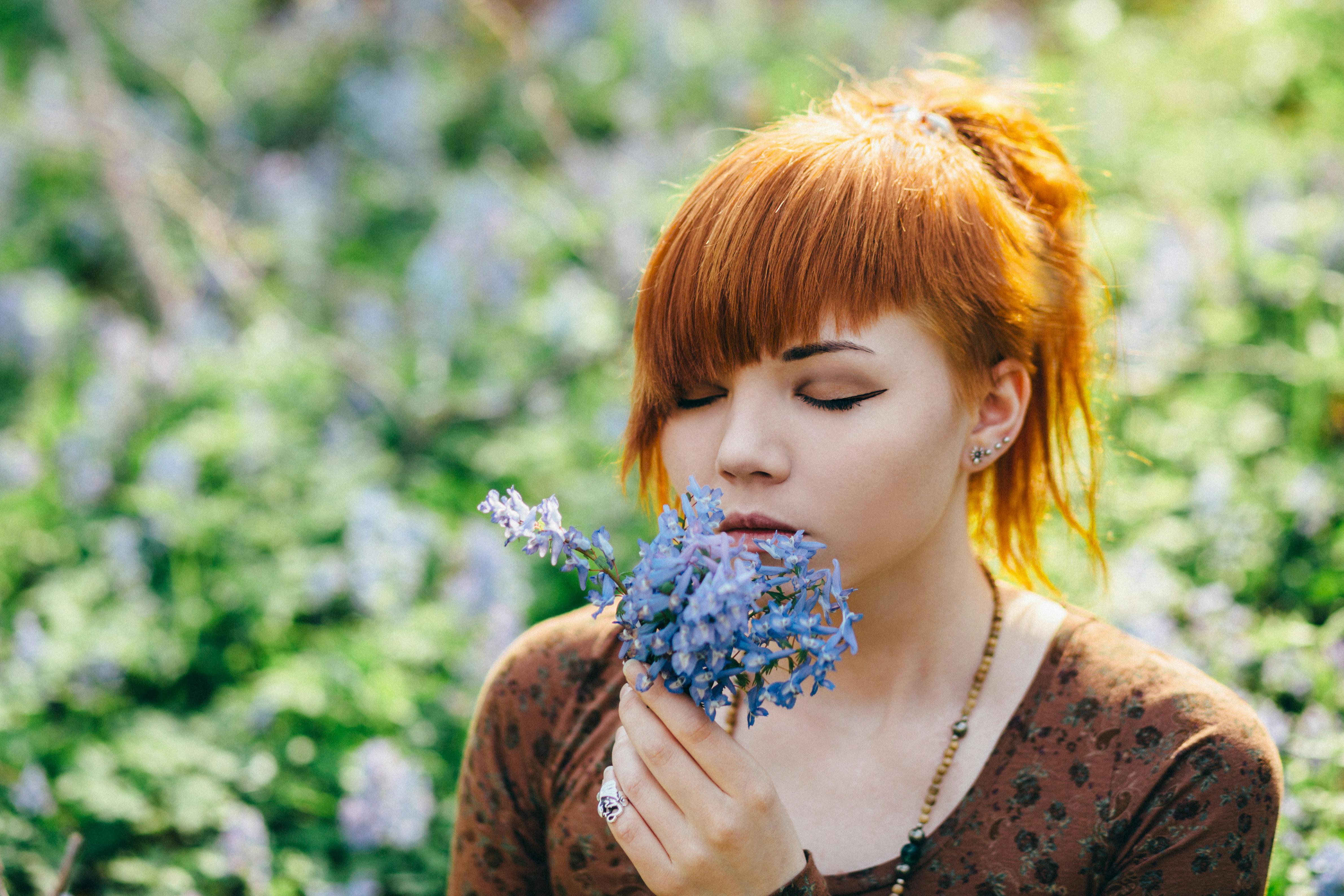A Woman Holding and Smelling Blue Flowers · Free Stock Photo