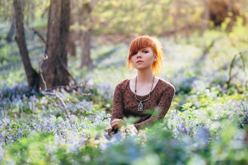 Free Woman Wearing Long Sleeve Shirt Sitting with Flowering Plants Stock Photo