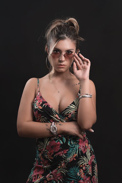 A Woman in Floral Dress Wearing Trendy Sunglasses while Posing at the Camera