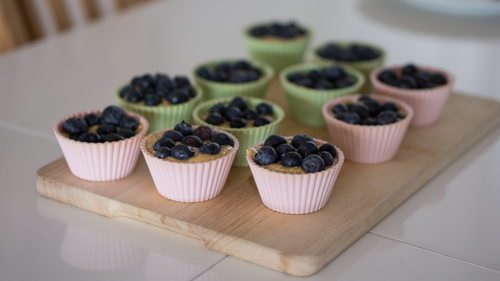 Free Delicious homemade blueberry muffins presented on a wooden board, perfect for breakfast or snack. Stock Photo