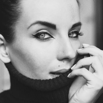 Elegant grayscale close-up portrait of a woman in a stylish pose.