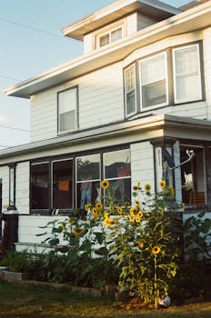 A nostalgic exterior view of a vintage house with a sunflower garden, captured on film.