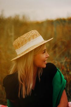 A woman in a straw hat enjoys a peaceful moment outdoors during the day.