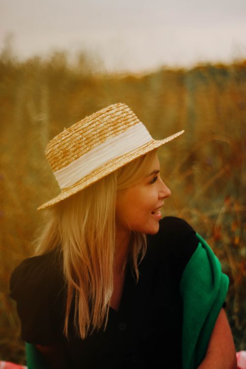 Free A woman in a straw hat enjoys a peaceful moment outdoors during the day. Stock Photo