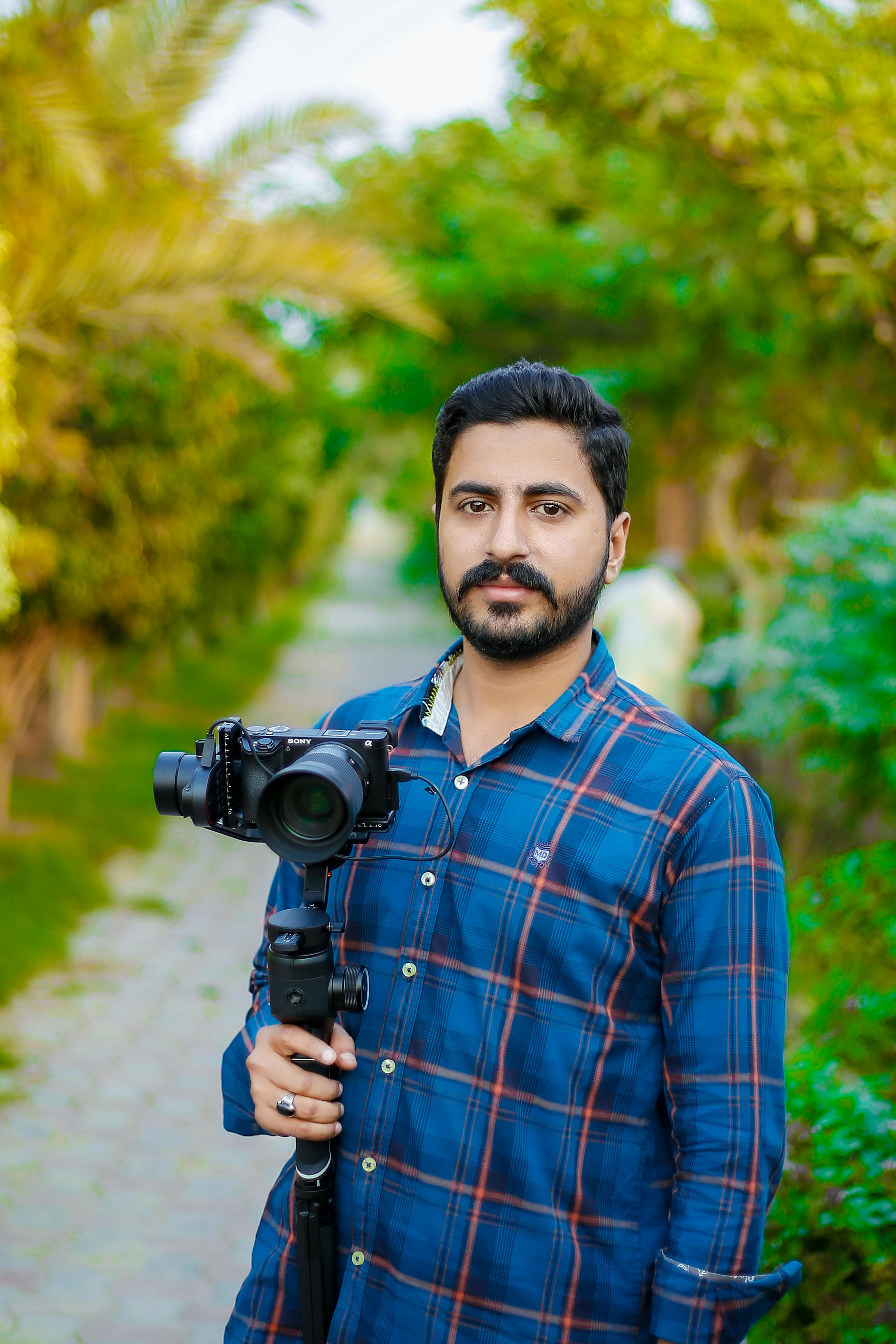 Premium Photo | Handsome and confident indian man photographer with a large  professional camera taking pictures photo shooting on the beach.photo  session on summer holiday on the background of green tropical trees