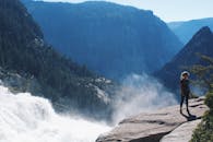 一个女人站在山林中瀑布附近的岩石上