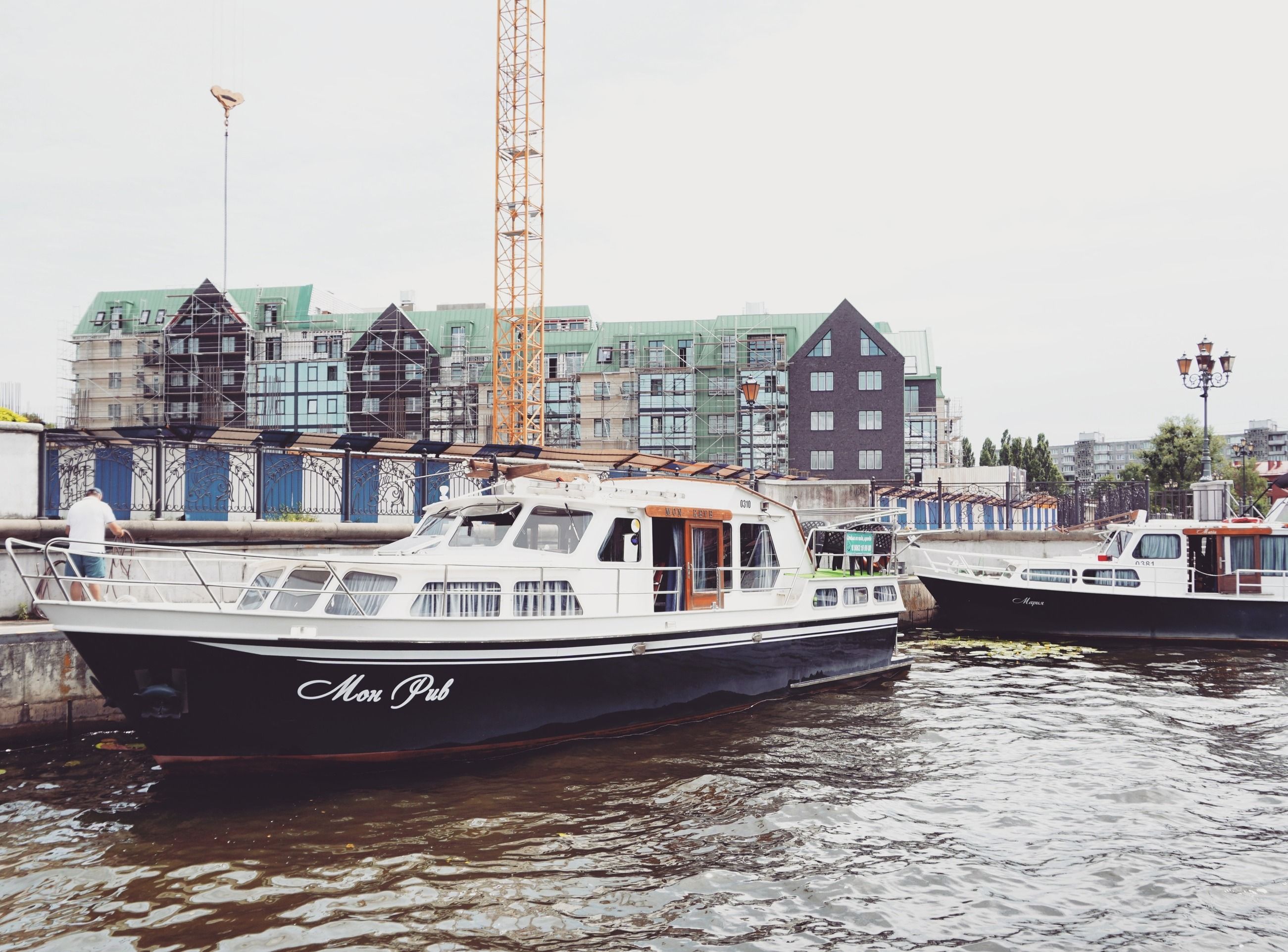 Motorboats docked at an urban marina with modern buildings in the background.