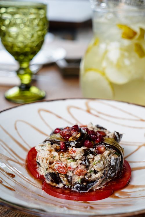 Free Elegant eggplant appetizer with pomegranate seeds and lemon drink setting. Stock Photo
