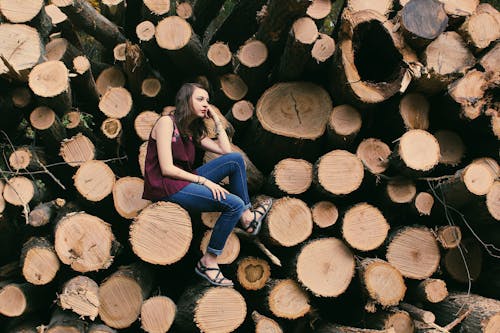 Photography of a Woman Sitting on a Log