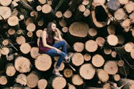 一名年轻女子在户外坐在一堆原木上拍照