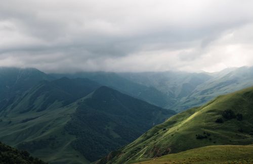 Free A captivating view of rolling green hills under a dramatic cloudy sky, showcasing nature's beauty. Stock Photo
