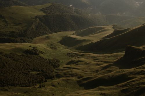 Free A stunning aerial view of rolling green mountains illuminated by dawn light. Stock Photo