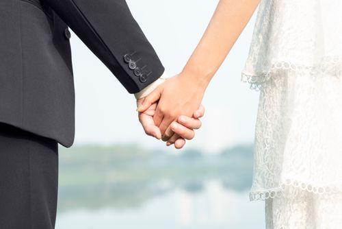 Free Bride and groom holding hands in a romantic outdoor setting, symbolizing love and partnership. Stock Photo