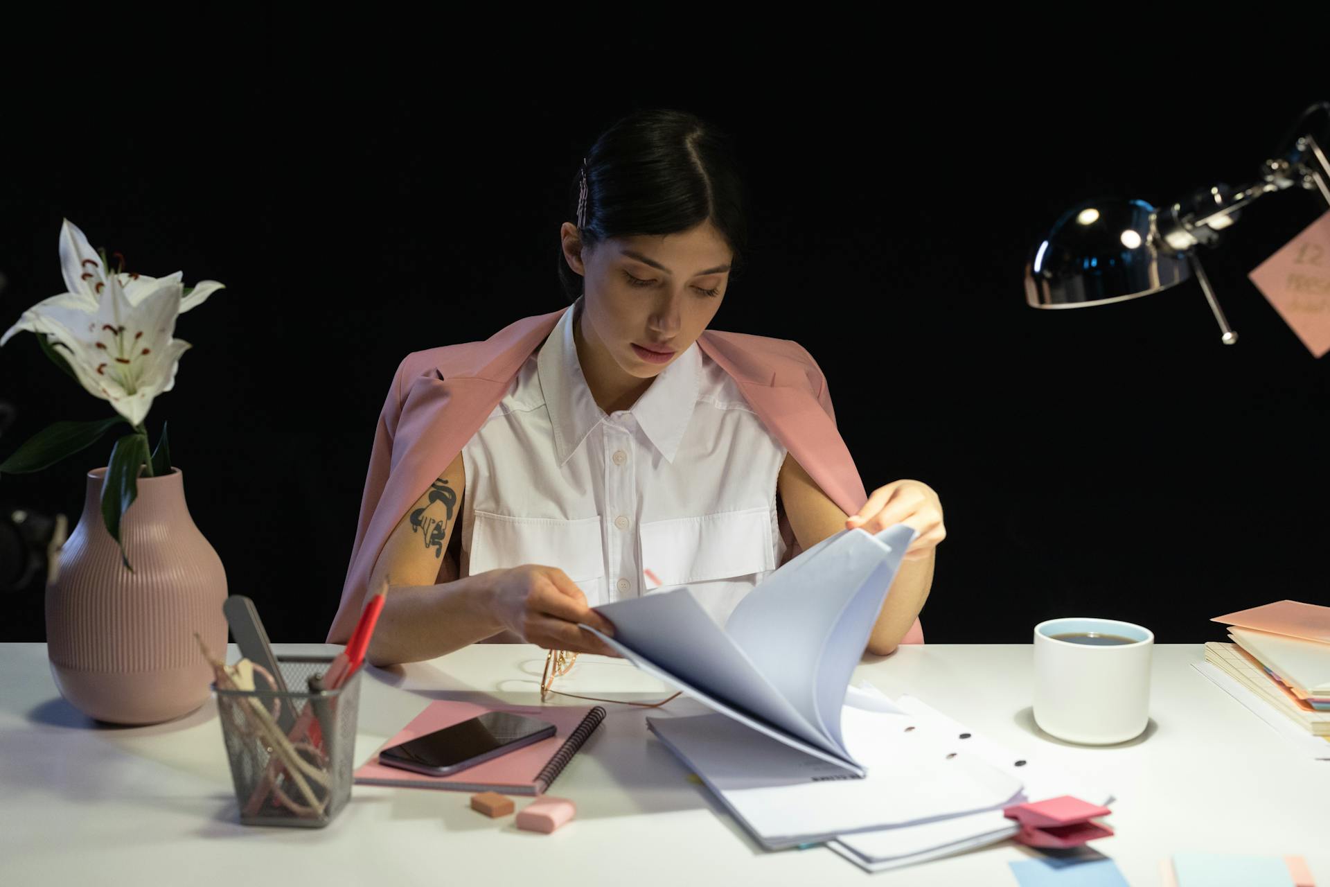 A professional woman focused on reading documents at her desk in a modern office setting.