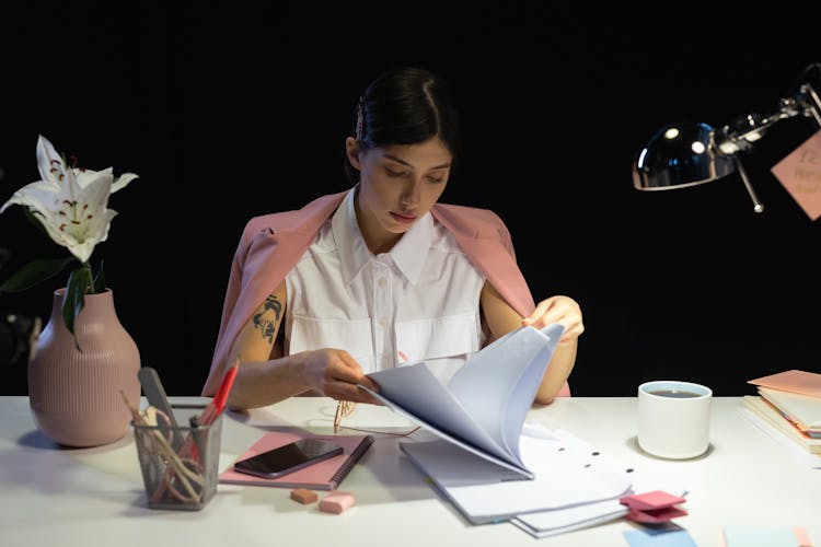 Woman Sitting In Front Of A Desk Reading The Documents