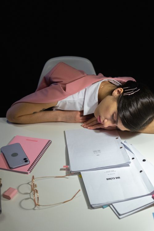 Free Businesswoman resting on desk with papers and phone, highlighting work fatigue. Stock Photo