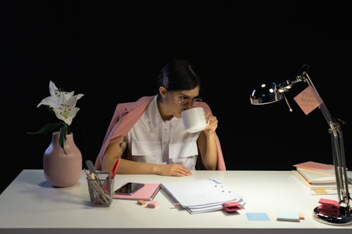 Woman Sitting Behind the Desk Drinking Coffee