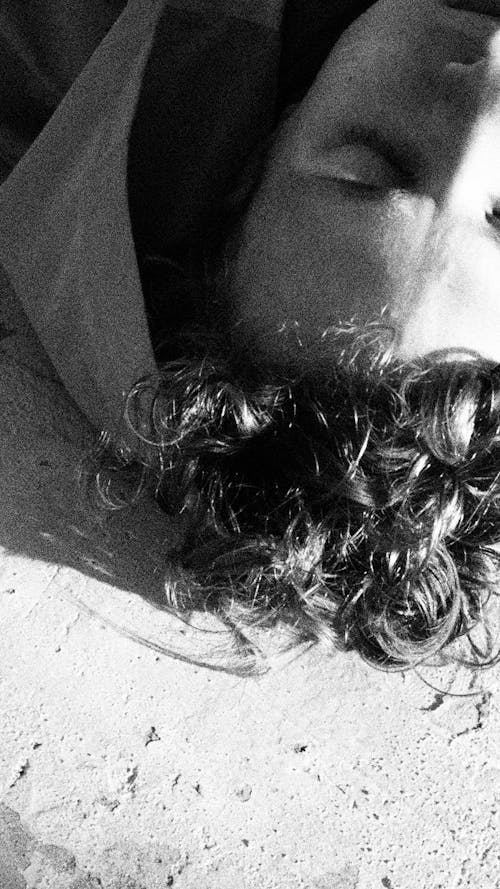 Foto profissional grátis de cabelo cacheado, deitando-se, escala de cinza
