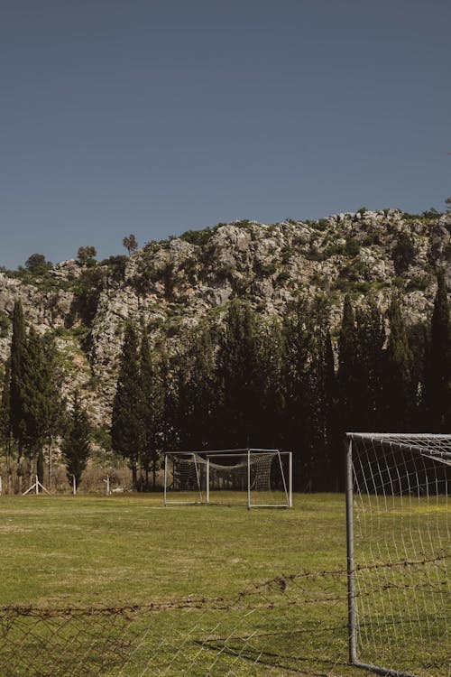 Soccer Field Near Green Trees and Mountain