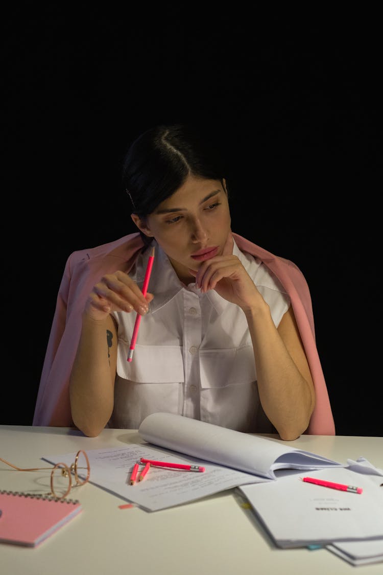 A Woman In White Top With Pink Blazer Holding A Pencil