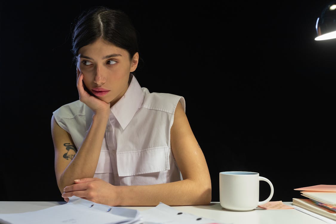 Woman in White Sleeveless Shirt Leaning on Table 