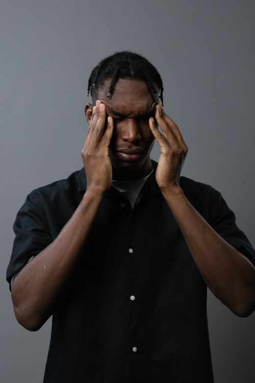 Free A man expressing tiredness and emotional distress with hands on face, captured in a studio setting. Stock Photo