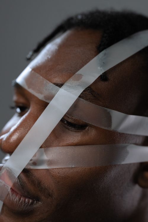 Free Artistic close-up portrait of a person with transparent tape on their face, symbolizing constraint. Stock Photo